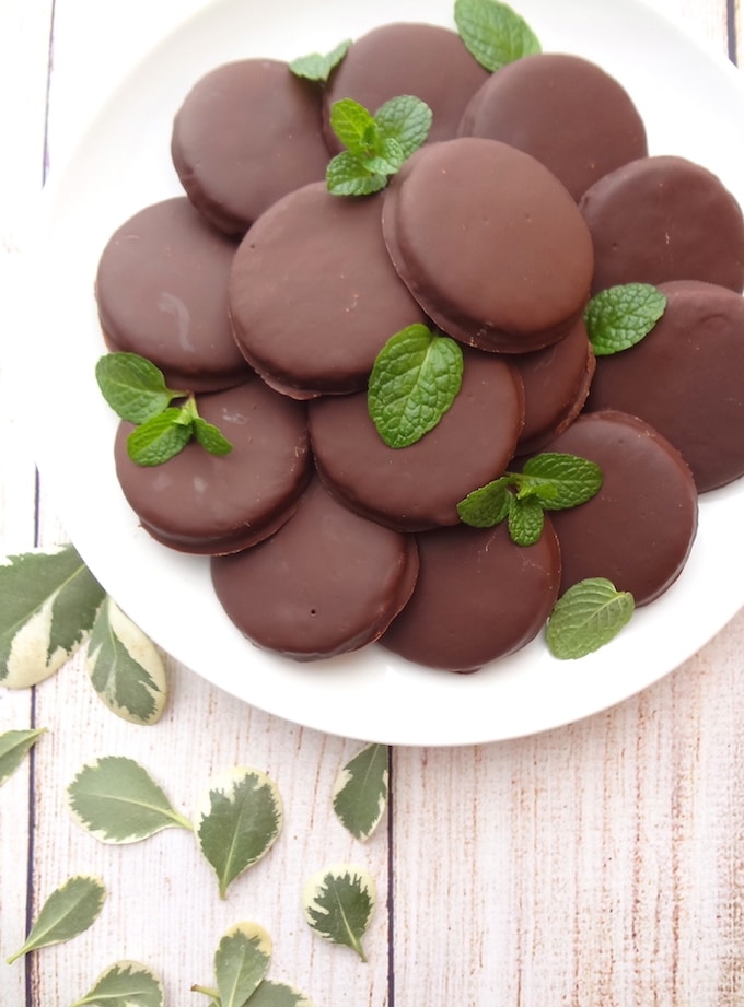 Top angle of vegan thin mints on a white plate. Chocolate Almond Cookies covered in a mint chocolate.
